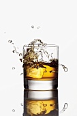 Ice cube falling into a glass of whisky