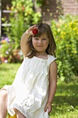 Kleines Mädchen zeigt Erdbeere im Garten