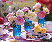 Rosen in Gläsern mit blau gefärbtem Wasser