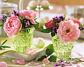 Rosafarbene Rosen mit Lavendelblüten in grünen Reliefgläschen