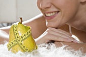 Pear with tape measure in front of young woman
