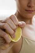 Hand squeezing half a lemon