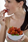 Young woman eating fresh strawberry
