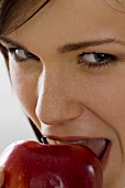Young woman biting into a red apple