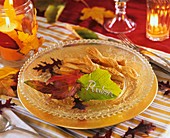 Savoury biscuits on glass plate, autumn leaves & leaf with name
