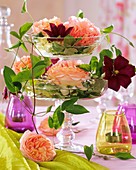 Etagere aus zwei Glasschalen mit Rosen und Clematis