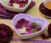 Table decoration of rose petals in a heart-shaped bowl