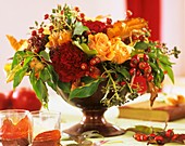 Schale mit Herbstgesteck aus Rosen und Hagebutten
