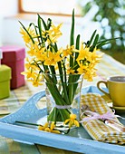 Narcissi in vase on tray with napkin and coffee cup