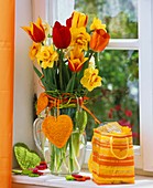 Red and yellow narcissi and tulips in a glass vase