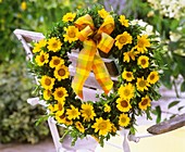 Wreath of golden marguerites and box hanging on chair back