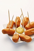 Cocktail sausages on wooden cocktail sticks with mustard