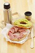 Bagel filled with ham and avocado spread