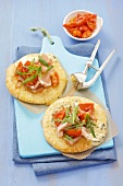 Pizza bases topped with cheese, ham and tomatoes