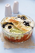 Lasagne with fish and olives in glass dish