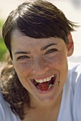 Junge Frau mit einer Kirsche im Mund