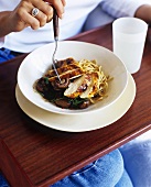 Woman eating chicken breast with mushrooms and spaghetti