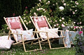 Zwei Liegestühle mit Kissen im Rosengarten