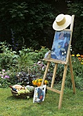 Easel with straw hat and picnic basket in a garden