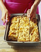 Apple cake with nut streusel being cut into pieces