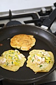 Shrimp and leek pancakes in frying pan