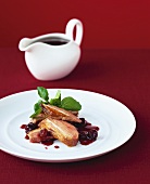 Duck breast with cherry sauce, sauce-boat in background
