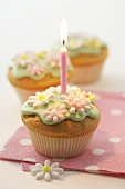 Geburtstagskerze auf Muffin mit Zuckerblüten