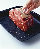 Putting salt on raw rolled beef joint