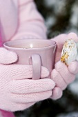 Hands holding a cup of hot chocolate and a stollen cookie