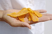 Hand holding dried mango slices