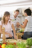 Kitchen scene: woman slicing vegetables, couple pouring wine