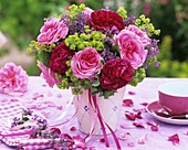 Arrangement of roses & lady's mantle on table laid in pink