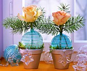 Rosen und Zweige in türkisen Christbaumkugeln als Vasen
