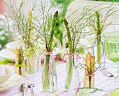 White and green asparagus in glass bottles on laid table