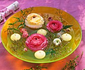 Ranunculus flowers, jasmine shoots & floating candles in bowl
