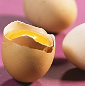 Broken egg in its shell, and two whole eggs