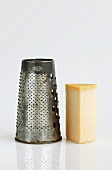 Piece of hard cheese beside cheese grater