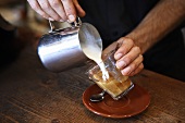 Barista giesst Milchschaum in Kaffee