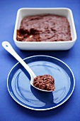 Chocolate rice pudding on spoon and in baking dish