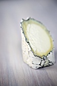 Goat's cheese, a piece removed, on wooden background