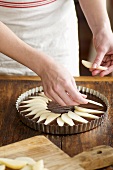 Woman arranging pear slices on unbaked cake mixture