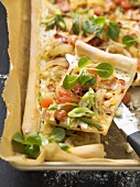 Tarte flambée topped with bacon and tomato