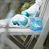 Christmas decorations in garden: baubles & candles in glasses on chair
