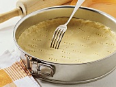 Pricking a shortcrust pastry base with a fork