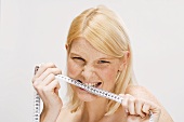Blond woman biting tape measure