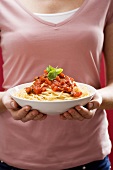 Woman holding spaghetti with tomato sauce