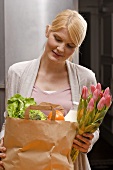 Blond woman with bag of shopping and bunch of tulips