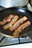 Fried rashers of bacon in frying pan