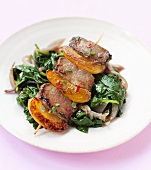 Meat and fruit kebab on spinach
