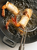 Pastry-wrapped prawns being deep-fried
